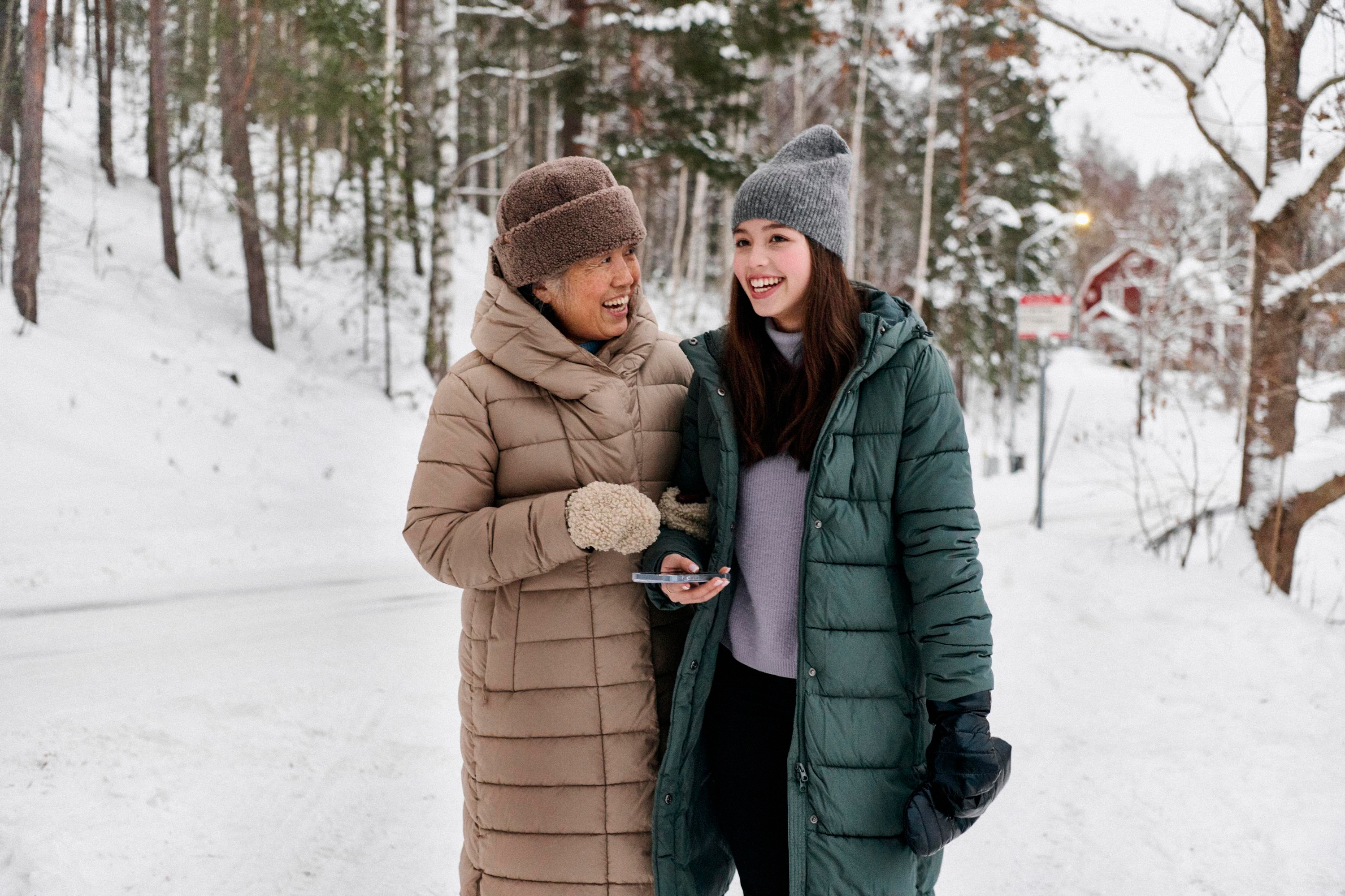En äldre kvinna och en ung tjej promenerar tillsammans i snön